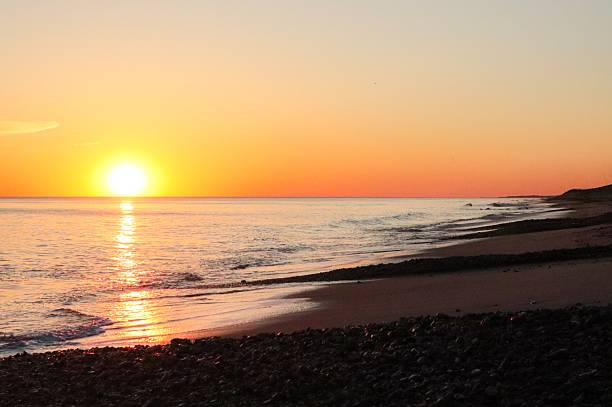 istock Sunset over calm sea with rocky beach foreground 2213296774
