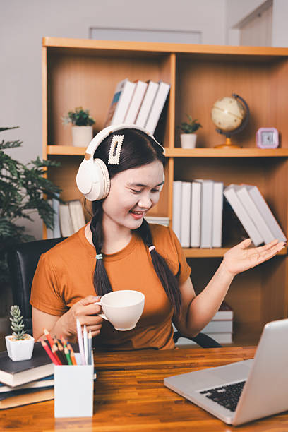 istock Asian girl doing homework and studying at home. woman using laptop at desk write notes watching webinar, study online, look at learn web class or having virtual call meeting remote working from home. 2213301116