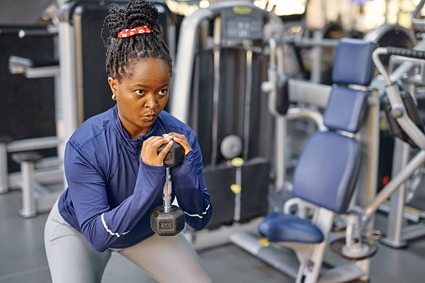 istock Young woman doing squats with a dumbbell at the gym 2213306871
