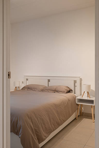 istock Minimalist bedroom with white bed frame, neutral bedding and two small nightstands 2213308492