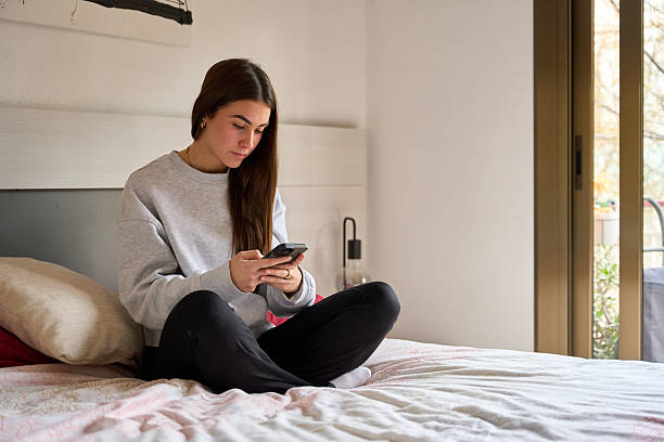 istock Young woman using smartphone on bed in bedroom 2213309258