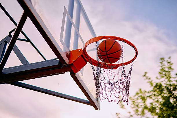 Basketball soaring through the net during an intense match, contributing valuable points for the team while showcasing athletic skill and competitive spirit on the outdoor court