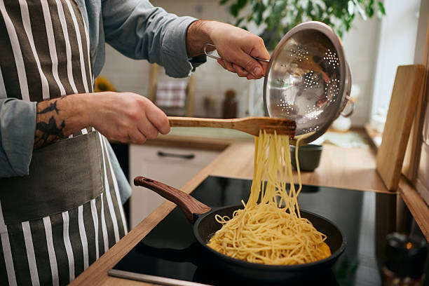 istock Close up of man making spaghetti in the kitchen. 2213312415