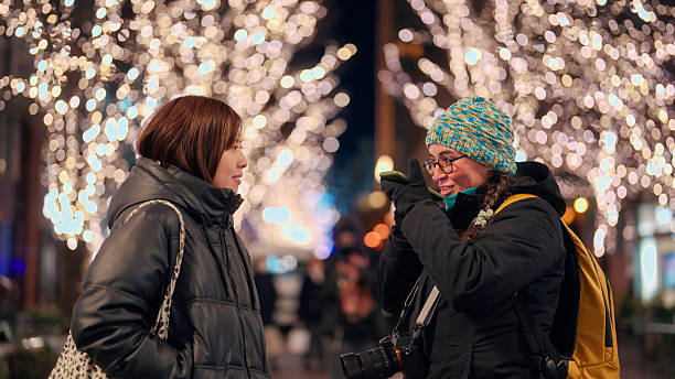 istock Female solo tourist asking utilizing artificial intelligent powered smartphone application to communicate with a local in the street at night 2213312518