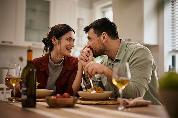 istock Affectionate man kissing his wife's hand during a meal at dining table. 2213312530