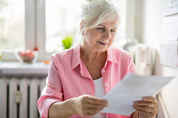 istock Senior woman looking through financial documents at home 2213315286