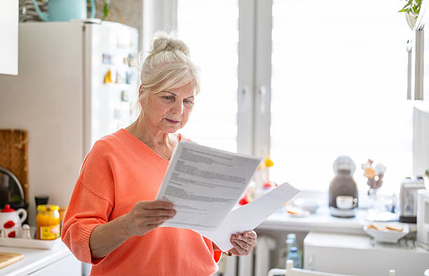istock Senior woman looking through financial documents at home 2213315559