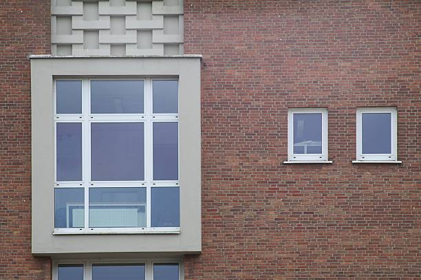 Architectural detail of a modern building facade showcasing varying window sizes and a textured brick wall
