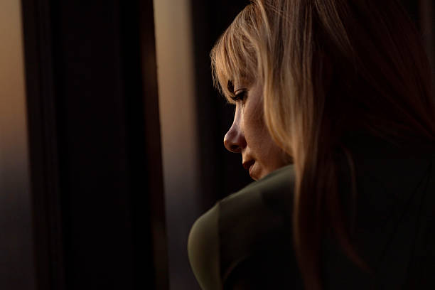 istock Thoughtful Woman Gazing Through Window at Sunset 2213316961