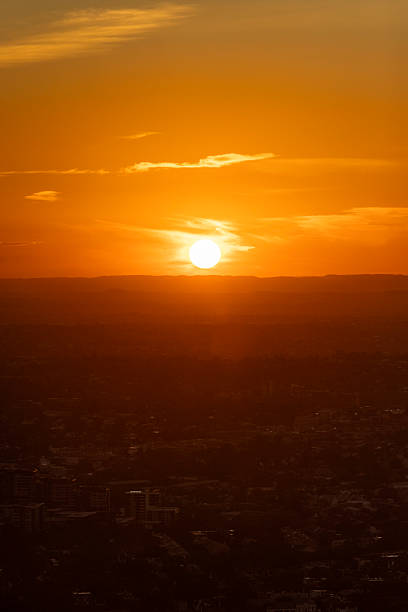 A breathtaking view of Sydney as the sun sets, casting golden hues across the sky and silhouetting the city's skyline against the horizon