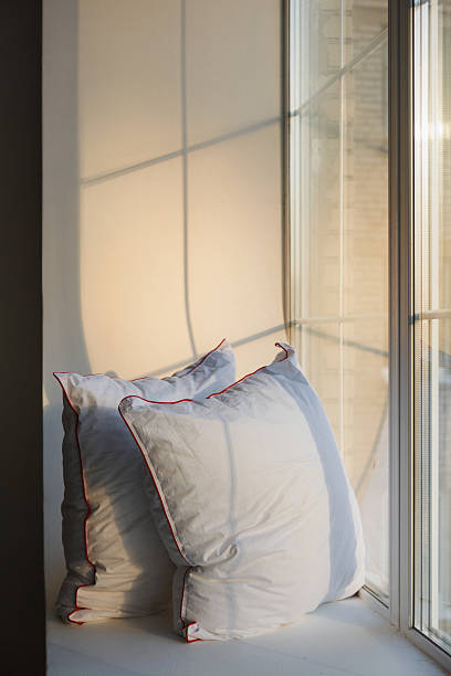 istock Two soft pillows are on a window sill in front of a large window 2213317478