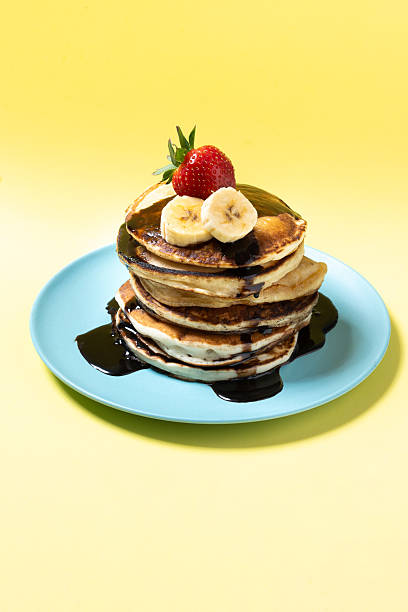 istock Pancakes with chocolate and fruit on yellow background 2213320858