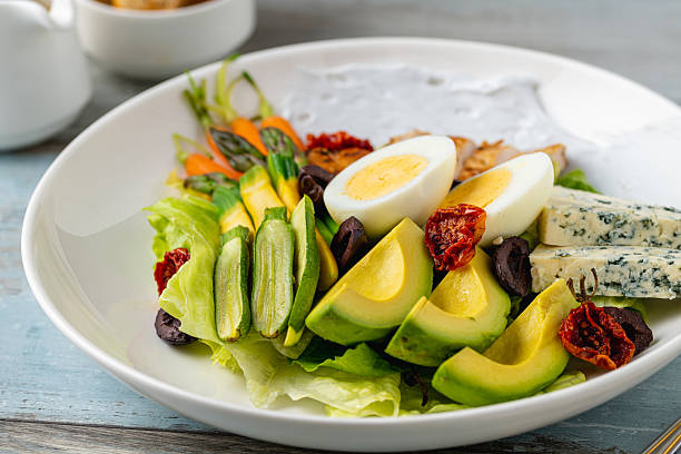 Healthy salad bowl with grilled chicken, avocado, egg, and blue cheese