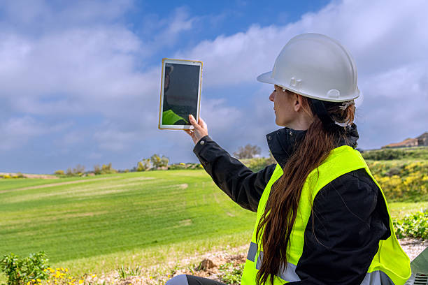 istock Female engineer using digital tablet in green field for sustainable energy 2213322819