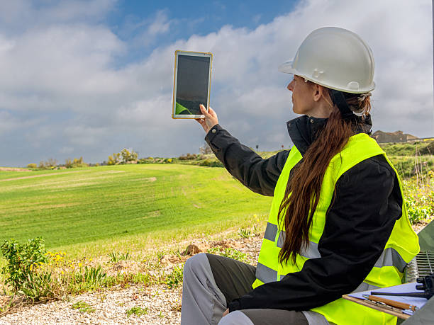 istock Female engineer using digital tablet analyzing green field for sustainable energy 2213322821