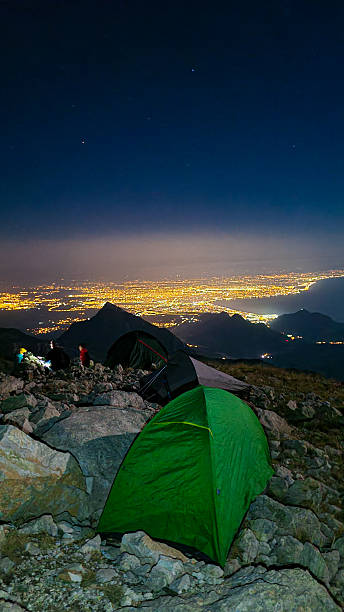 istock Tents on Mountain Summit Under Full Moon – Night Camping with City Lights Below 2213323442