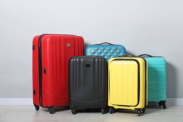 istock Many colorful suitcases on floor near light wall 2213323783