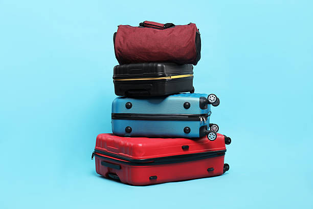 istock Stack of colorful suitcases and bag on light blue background 2213323792
