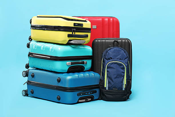 istock Colorful suitcases and backpack on light blue background 2213323800