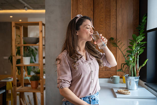 istock Beautiful woman drinking fresh water in a modern kitchen 2213326790