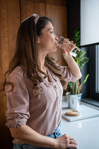 istock Woman drinking fresh water in the kitchen 2213326846