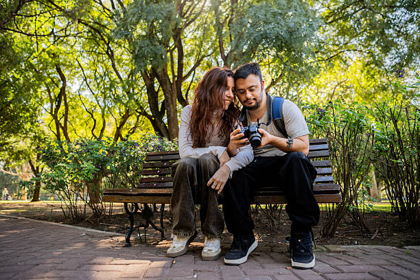 Couple looking for photos on camera at public park - man with down syndrome and woman with intellectual disability