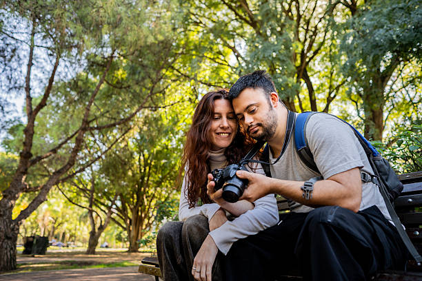 istock Couple looking for photos on camera at public park 2213330927