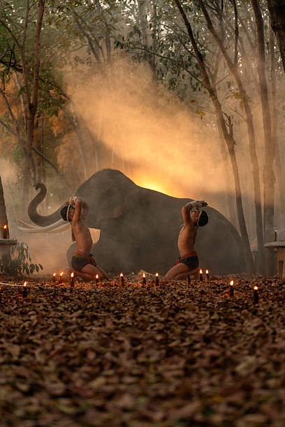 Muay Thai fighters performing a traditional wai khru ritual surrounded by candles, with a majestic elephant and glowing smoke in the background