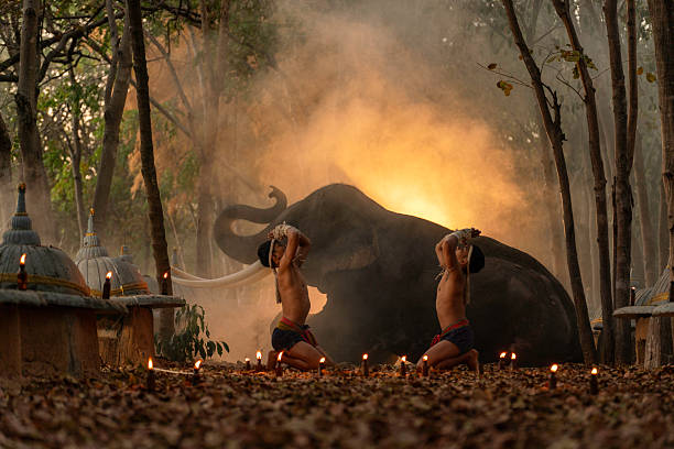 Muay Thai fighters performing a traditional wai khru ritual surrounded by candles, with a majestic elephant and glowing smoke in the background