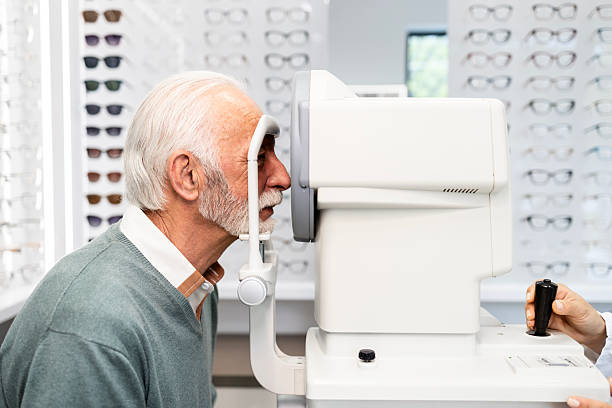 istock Senior man in optic store testing his eyesight and diopter with auto refractor instrument. 2213336698