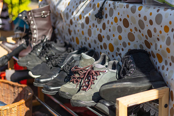 A variety of old worn shoes and boots on a flea market - selective focus on  front