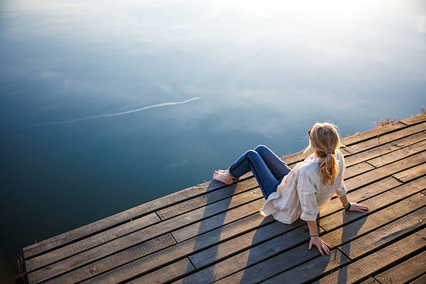 Woman relaxing on jetty at lake