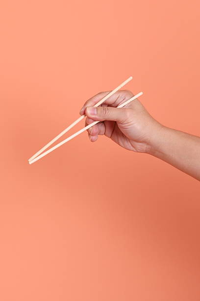 istock hand holding wood chopsticks 2213341659