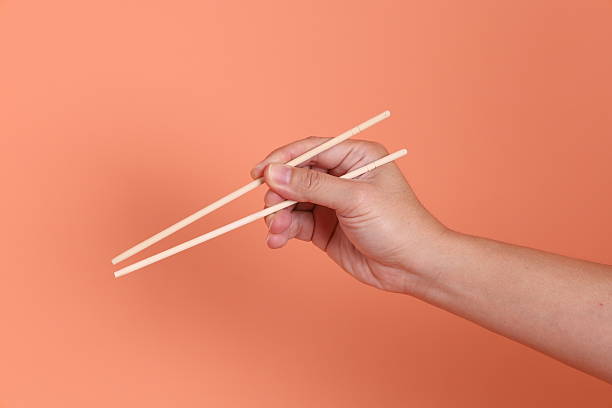 istock hand holding wood chopsticks 2213341693
