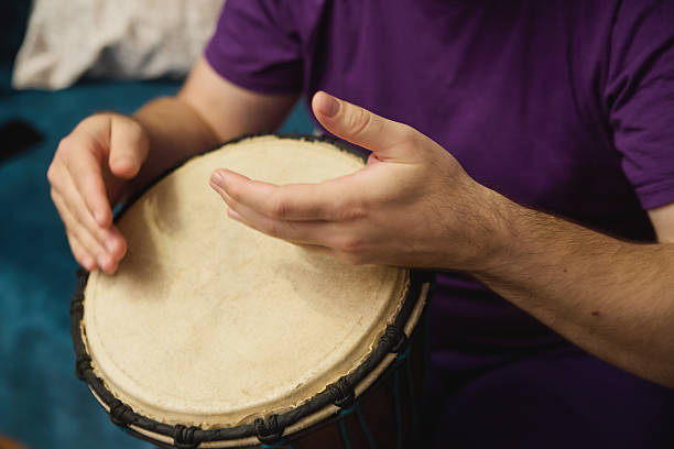 istock Person playing a percussion drum while seated on a cozy blue surface at home during a casual practice session 2213343701