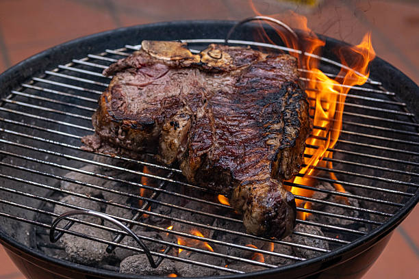 A Florentine beef steak on the grill. The flame is high and the meat is cooked to perfection.