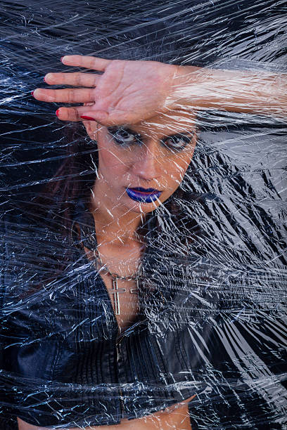 istock A woman looks through a hole in the plastic covering her face while she is dressed and made up for an event. 2213349715