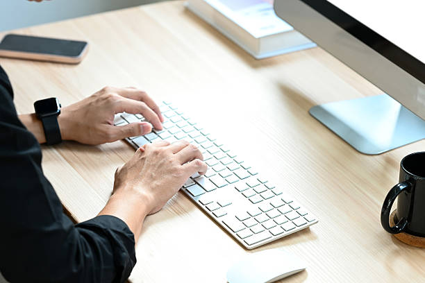 istock A person is typing on a keyboard at a desk with a book and a cup. 2213349986