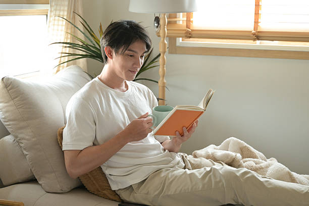 istock A man is reading a book while holding a cup of coffee. 2213351032