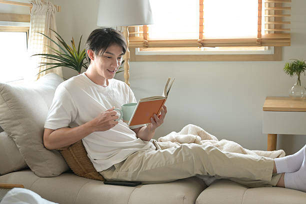 istock A man is reading a book while holding a cup of coffee. 2213351033
