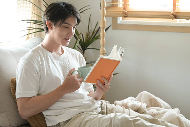 istock A man is reading a book while holding a cup of coffee. 2213351034
