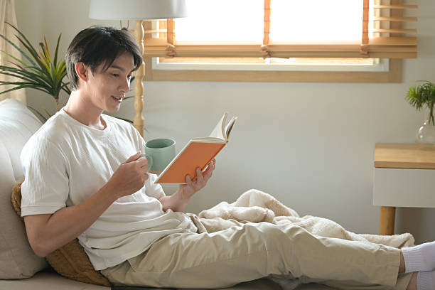 istock A man is reading a book while holding a cup of coffee. 2213351039