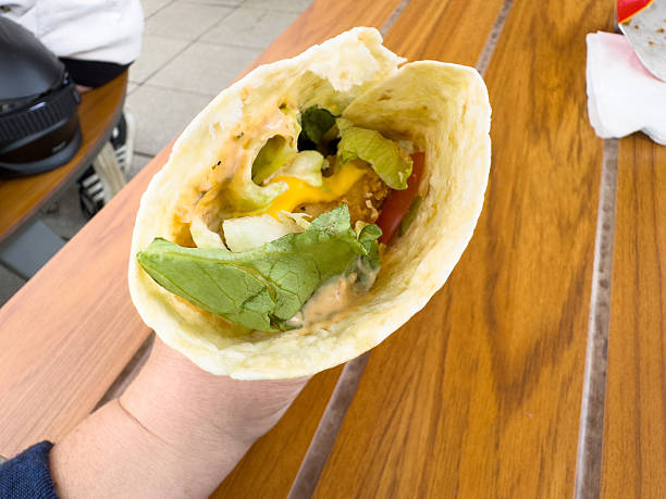 istock Hand holding fresh falafel wrap with vegetables and sauce 2213352268