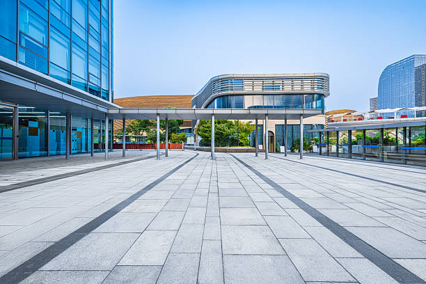 istock Empty brick floor and modern glass office buildings and green plants under blue sky. 2213353655