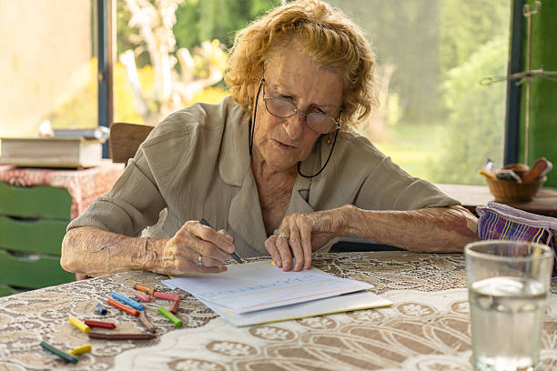 istock Senior woman drawing with crayons at home 2213354033