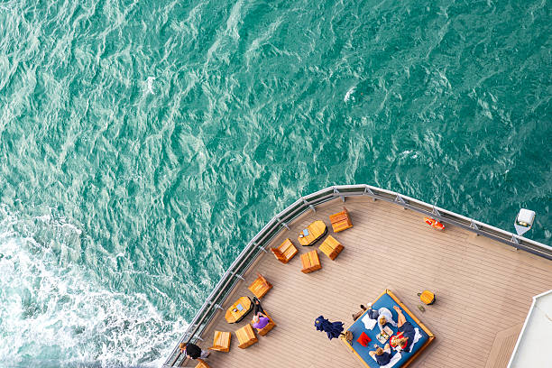 Civitavecchia, Italy- May 23, 2024:  A fragment of the plank deck of a luxury cruise ship with brown sun loungers, behind the railing the waves of the sea, no people, windy weather