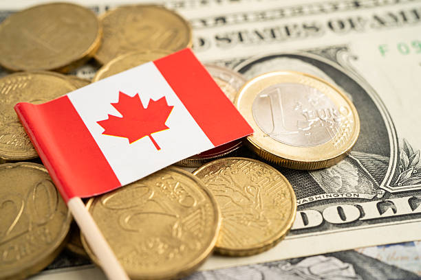 istock Stack of coins with Canada flag and US dollar banknotes. 2213359209