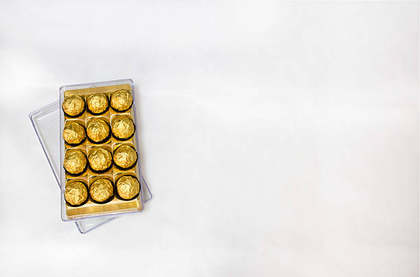 Box of golden chocolates on white background with copy space