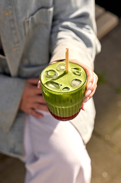 Woman enjoys a vibrant iced matcha latte on a sunny day