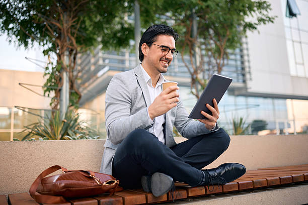 istock Businessman drinking coffee and using digital tablet outdoors 2213370248